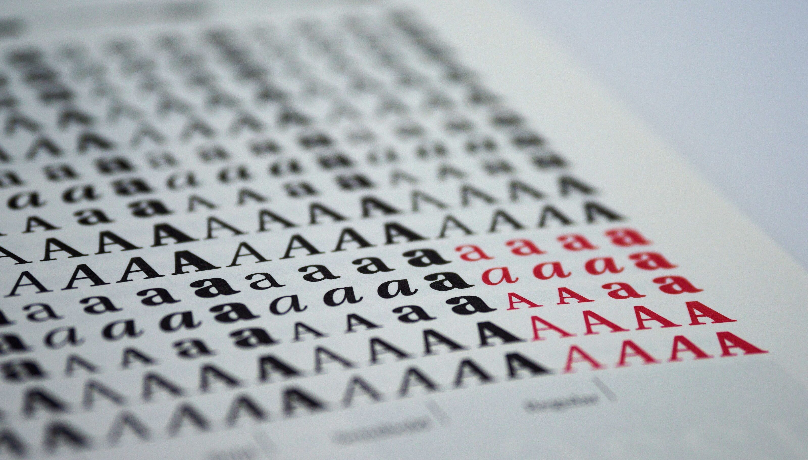 Printed type specimen of the letter A set in many typefaces, in black with a group of red variants.